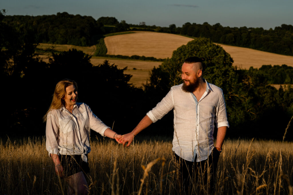 engaged couple walking in a field near High Wycombe