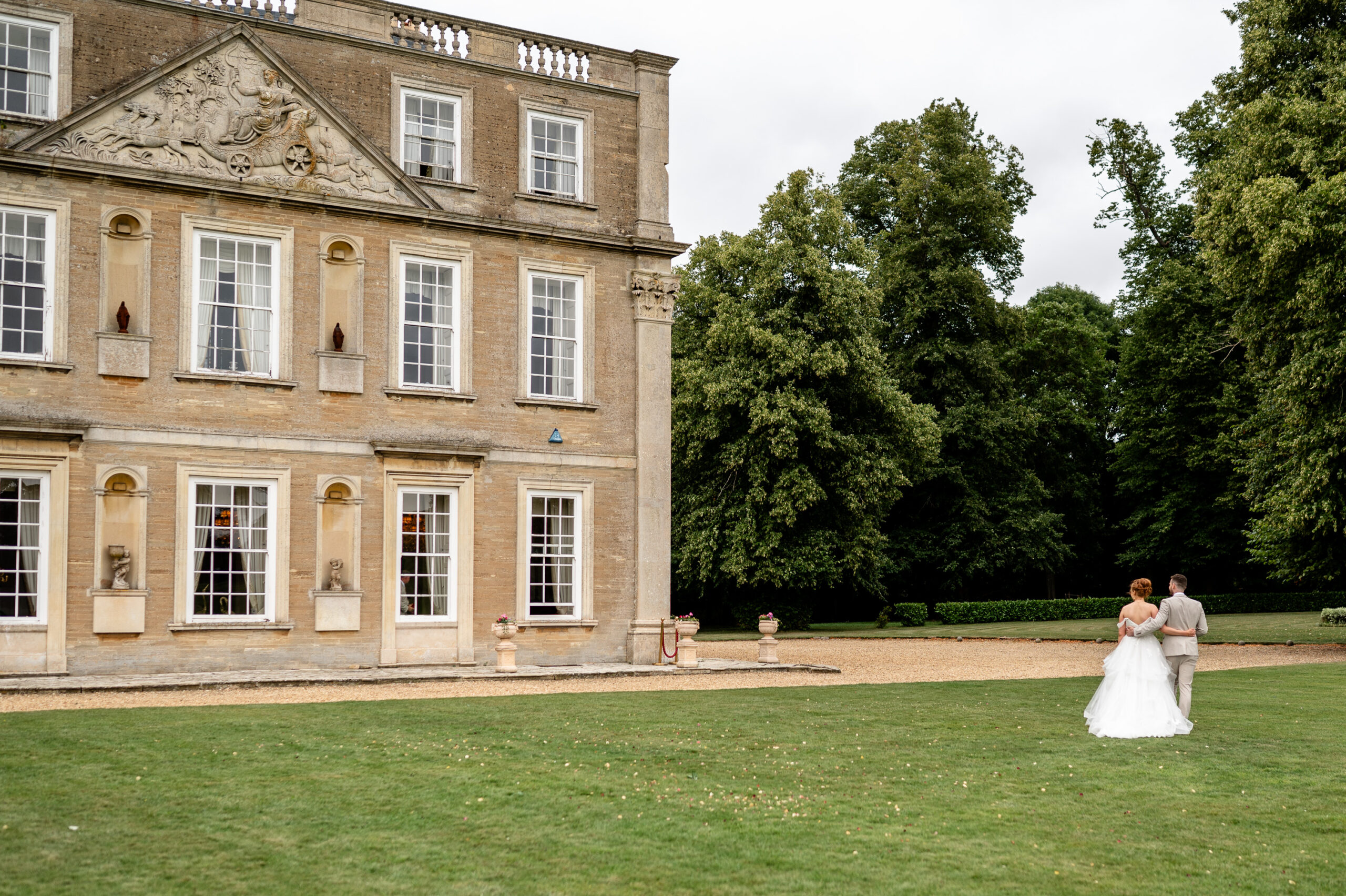 Bride and groom walking along Hinwick House