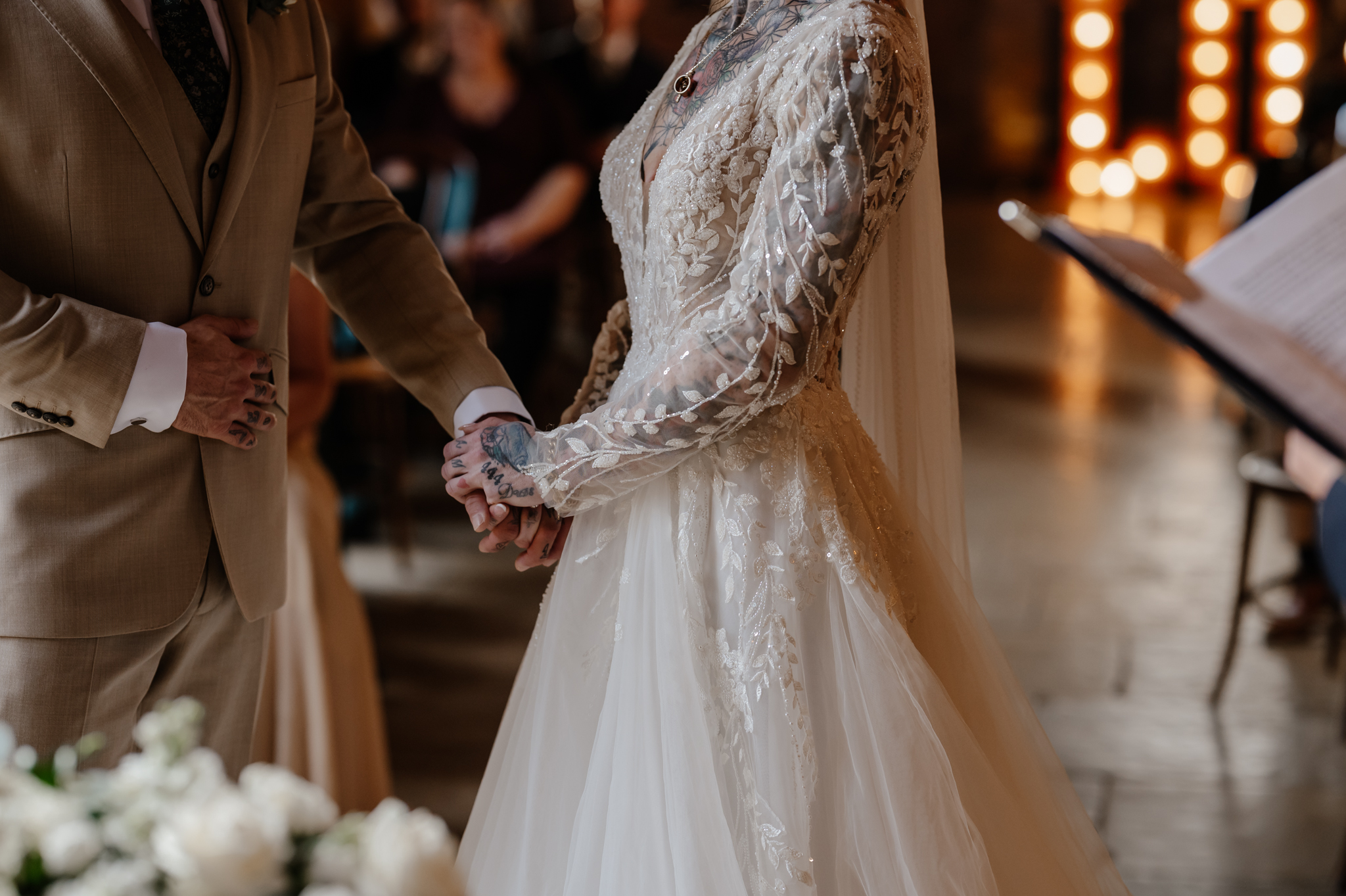 Close-up of bride and groom holding hands at their autumn wedding