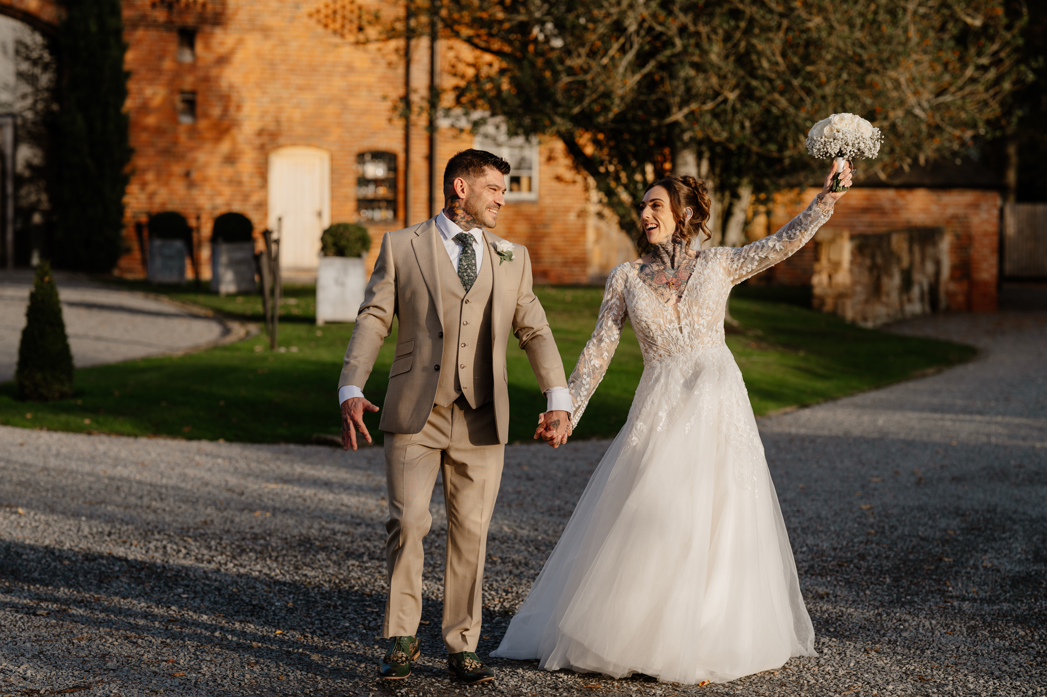 Bride and groom standing in front of Shustoke Barn on their autumn wedding day